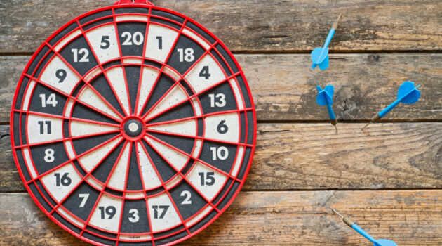 dart board with darts missing the target, and off to the side