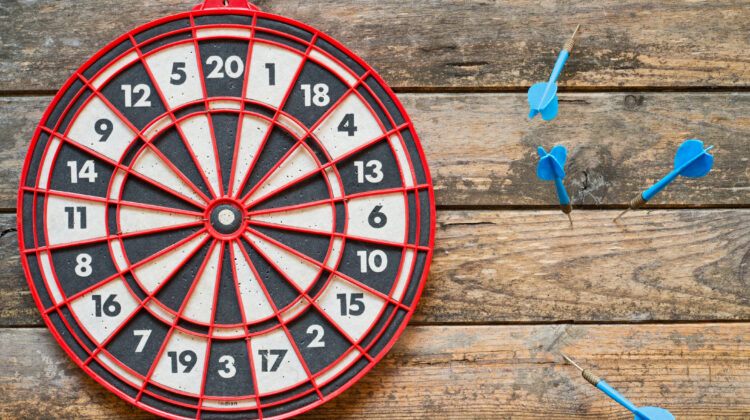 dart board with darts missing the target, and off to the side
